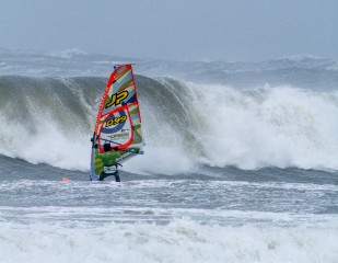 Danmarksmesteren i windsurf waveperformance, Lars Petersen trodsede stormen i Nordjylland. Om et øjeblik bliver han nedlagt af bølgen som vi ser på billedet og må svømme i land med brækket mast og krøllet udstyr
